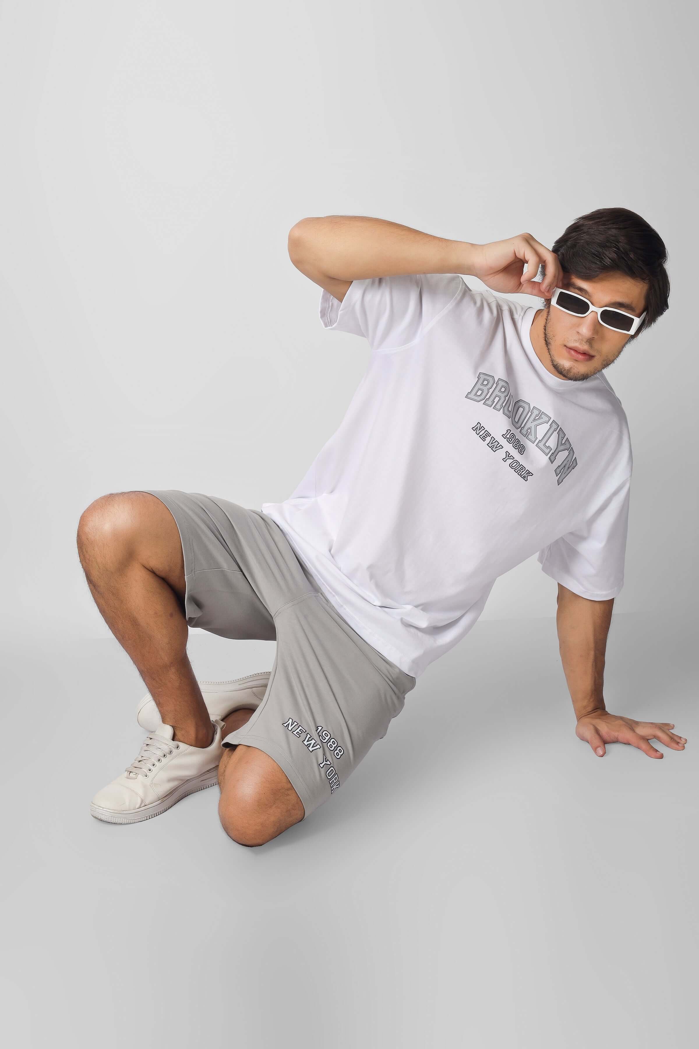 Stylish Brooklyn co-ord set in white and grey, featuring custom fit options, modeled by a person wearing sunglasses and casual sneakers.