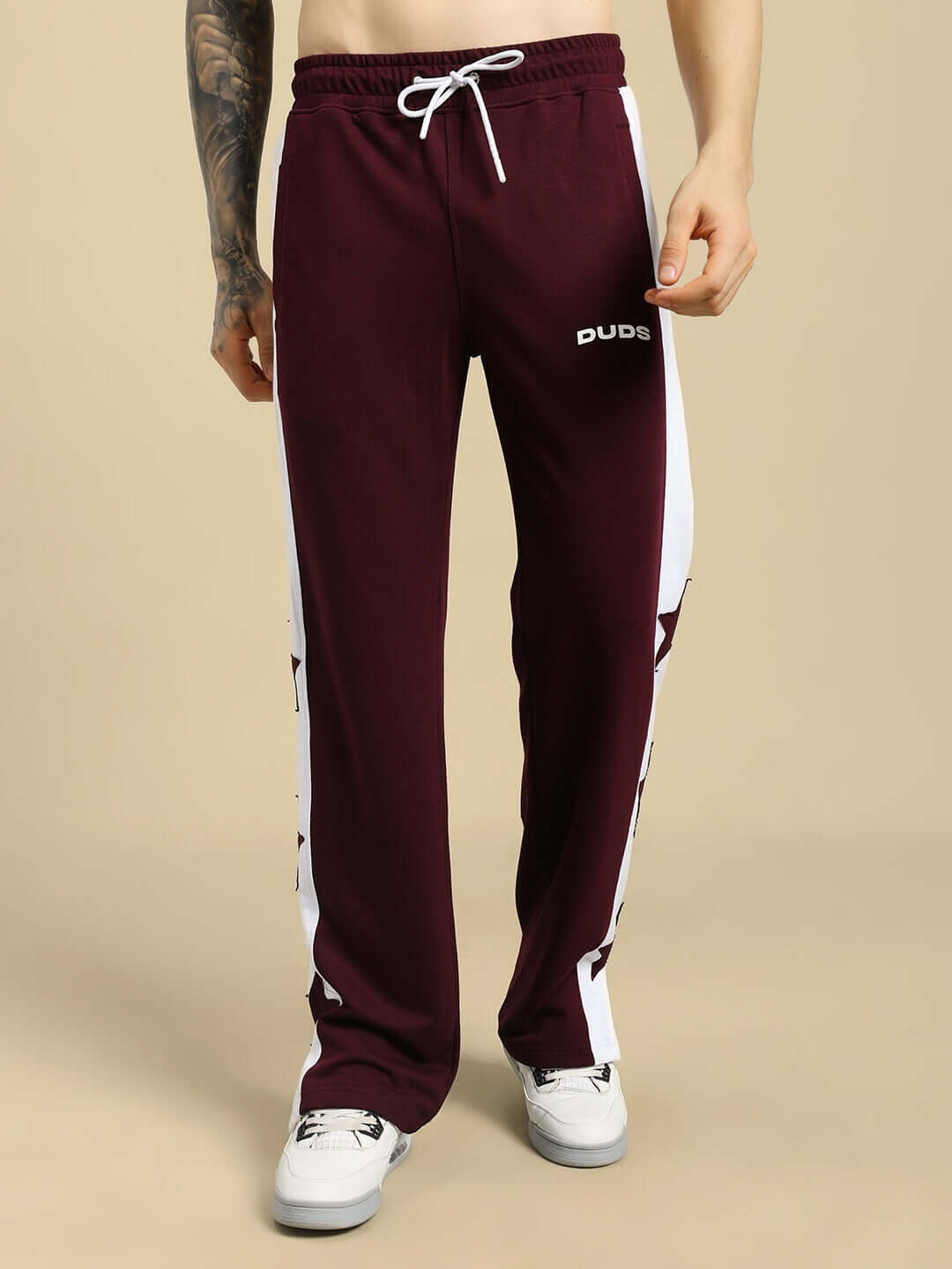 Man wearing BROX STAR maroon-white relaxed fit joggers by DUDS with side stripes and white sneakers.