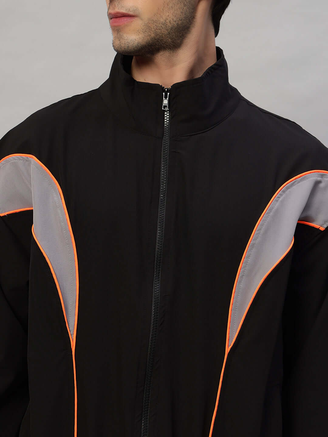 Model wearing BULLET OVERSIZED CO-ORD SET BLACK jacket with orange and gray accents, showcasing streetwear style.