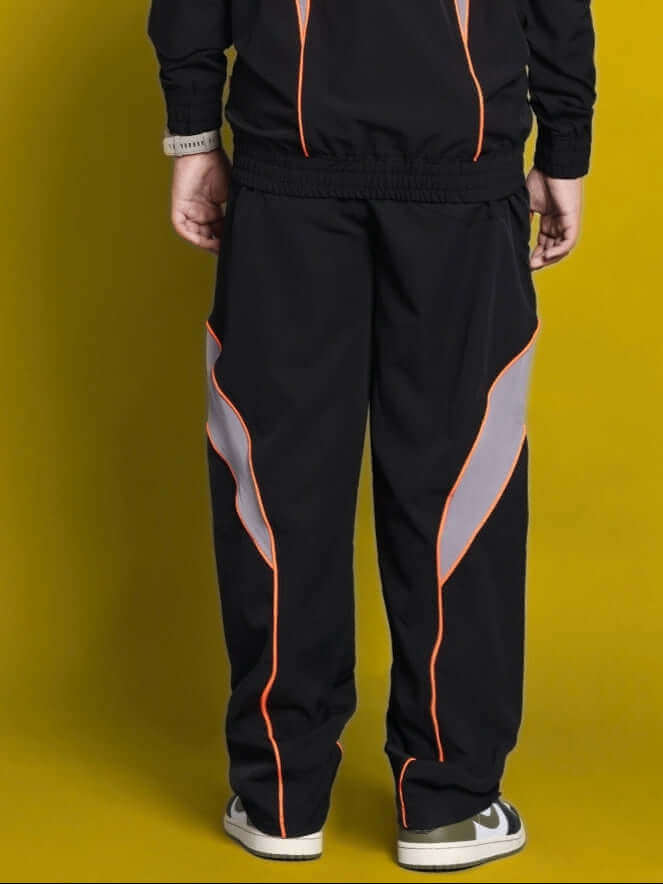 Child wearing black relaxed fit cargo pants with orange accents, back view.