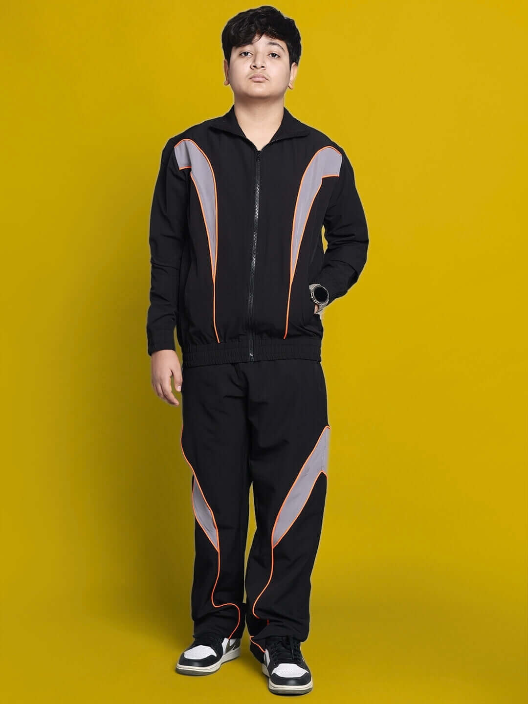 Young person wearing a black bullet parachute jacket from DUDS, designed for boys and girls. Features custom sizing and vibrant accents.