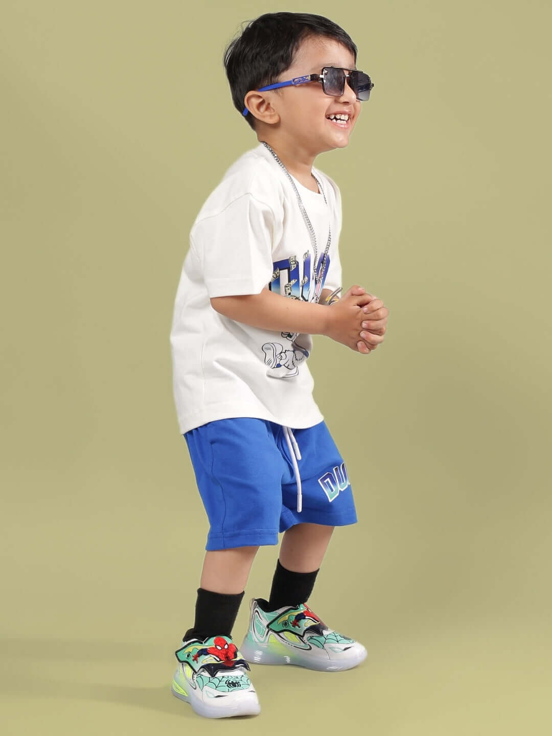 Child wearing BUMBLE CO-ORD FOR BOYS & GIRLS OFF WHITE-R BLUE with sunglasses, smiling on a light green background.