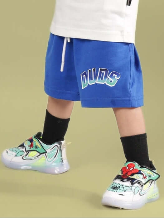 Child wearing Bumble Shorts for Boys & Girls Royal Blue by DUDS, featuring colorful sneakers and black socks.