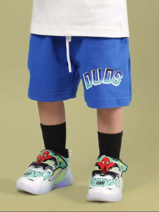Child wearing BUMBLE SHORTS FOR BOYS & GIRLS ROYAL BLUE by DUDS with fun sneakers, showcasing vibrant color and style.