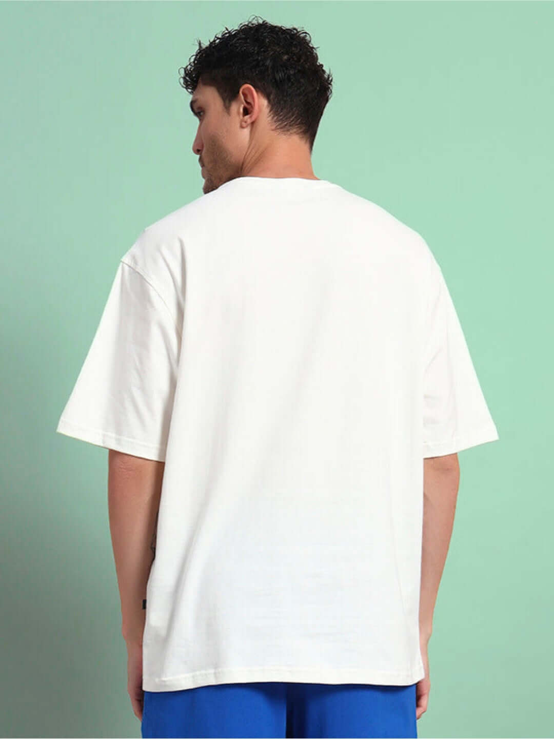 Back view of BUNNY BUGS OVERSIZED T-SHIRT OFF-WHITE worn by a model standing against green background