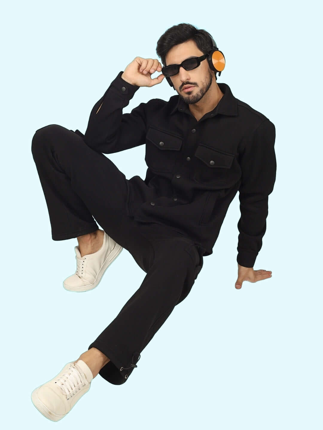 Model wearing Burly Black Overshirt-Cargo Pant Co-Ord Set with headphones and sunglasses, sitting against a light blue background.