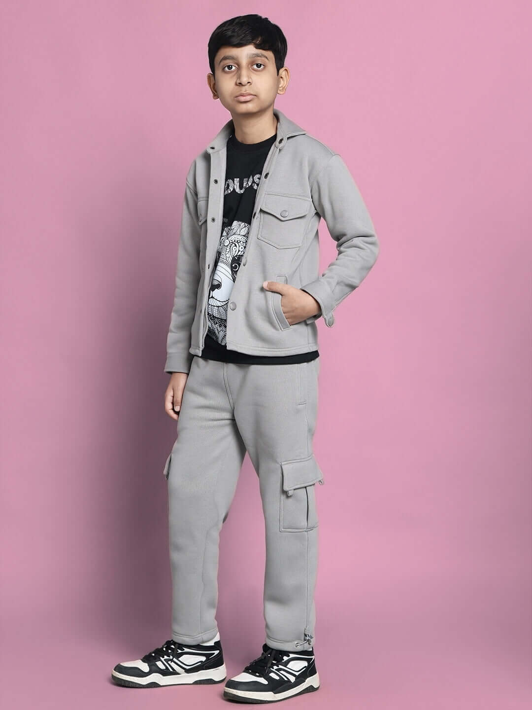 Boy wearing grey Burly fleece pants and a matching jacket, standing against a pink background.