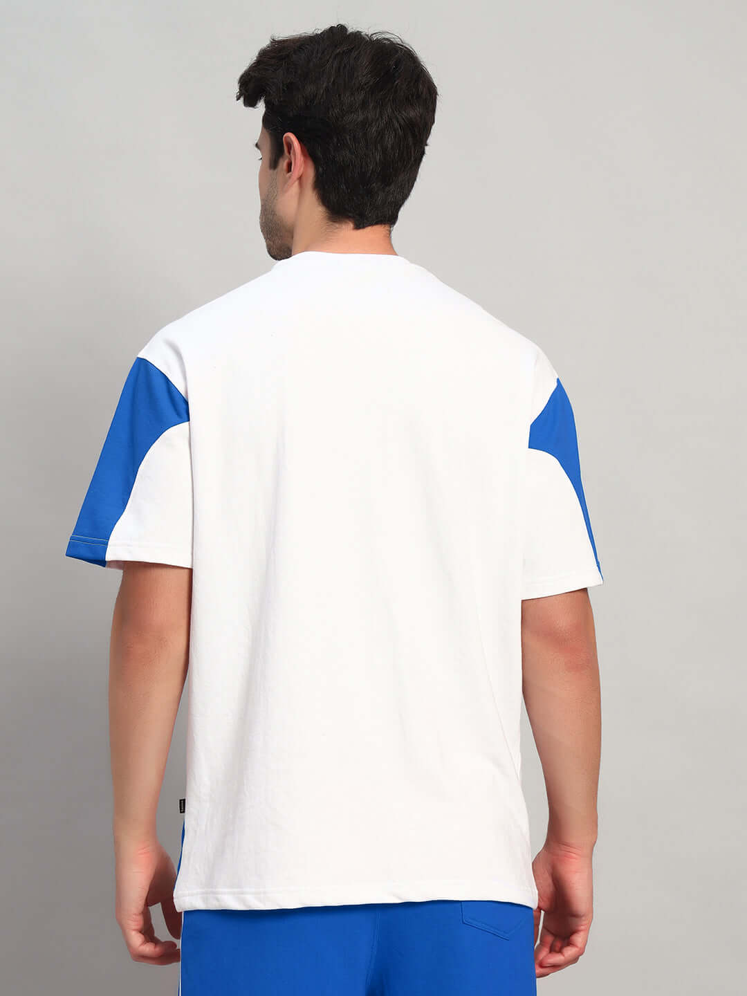 Back view of model wearing CANDOR OVER-SIZED T-SHIRT WHITE BLUE, showcasing blue accents on white base, ideal for streetwear style.