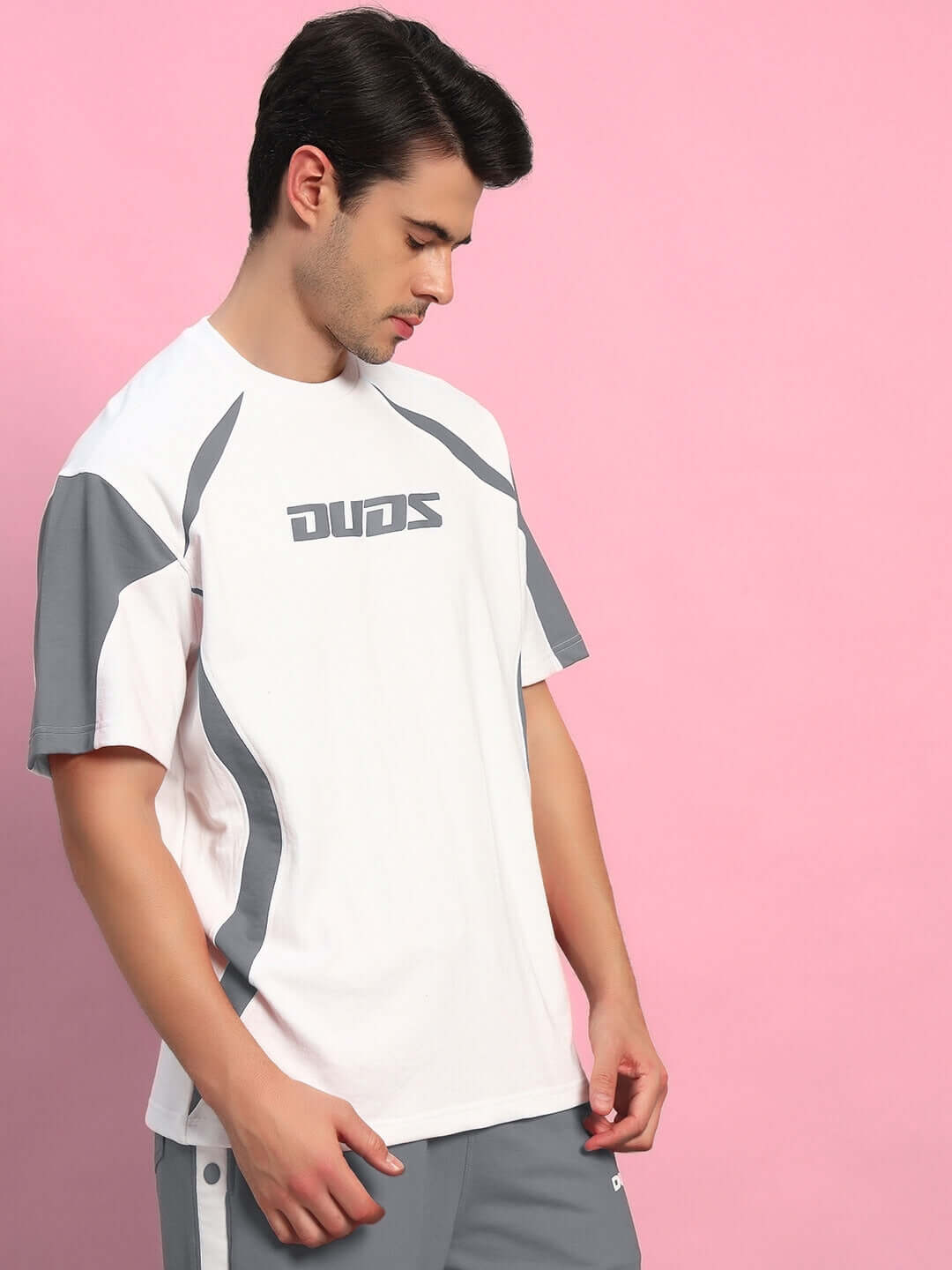 Model wearing Candor over-sized white grey T-shirt, made from premium cotton French terry with elastane, on a pink background.