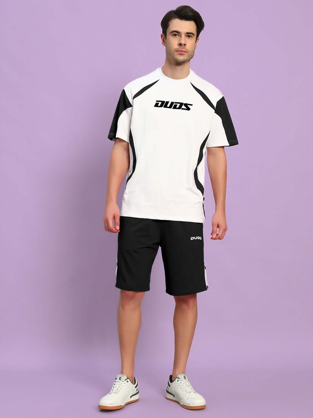 Model wearing CANDOR OVER-SIZED T-SHIRT WHITE BLACK with shorts, showcasing streetwear style.