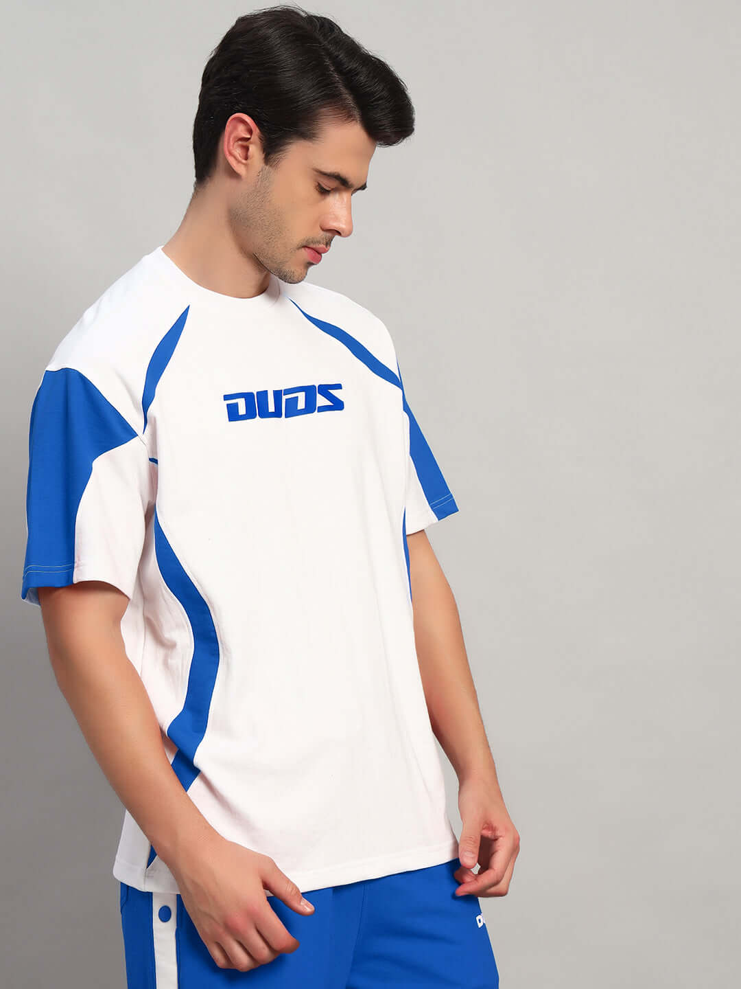 Man wearing a CANDOR OVER-SIZED T-SHIRT WHITE BLUE with blue accents, showcasing streetwear fashion.