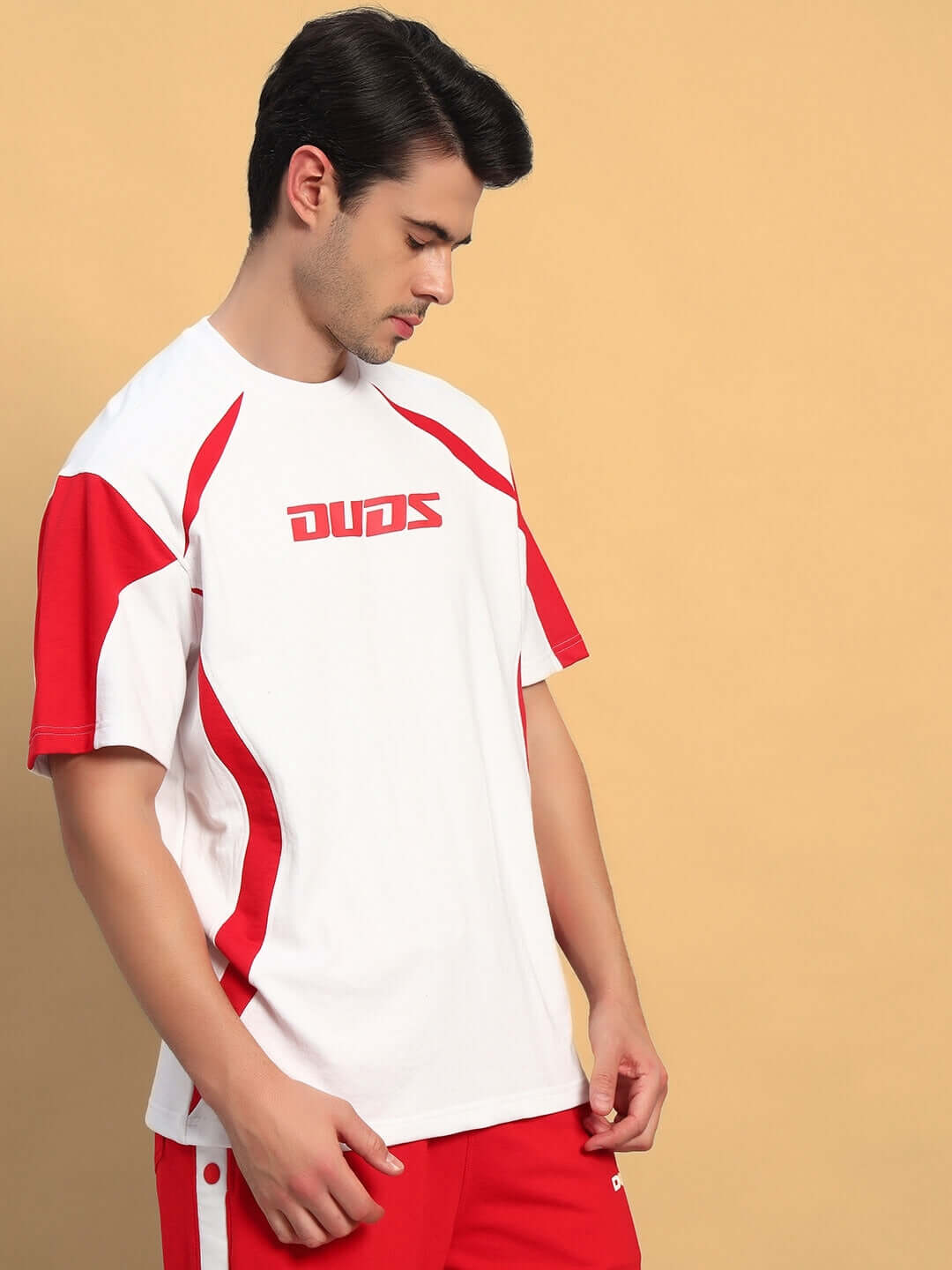 Man wearing a CANDOR OVER-SIZED T-SHIRT WHITE RED with red stripes on a beige background.