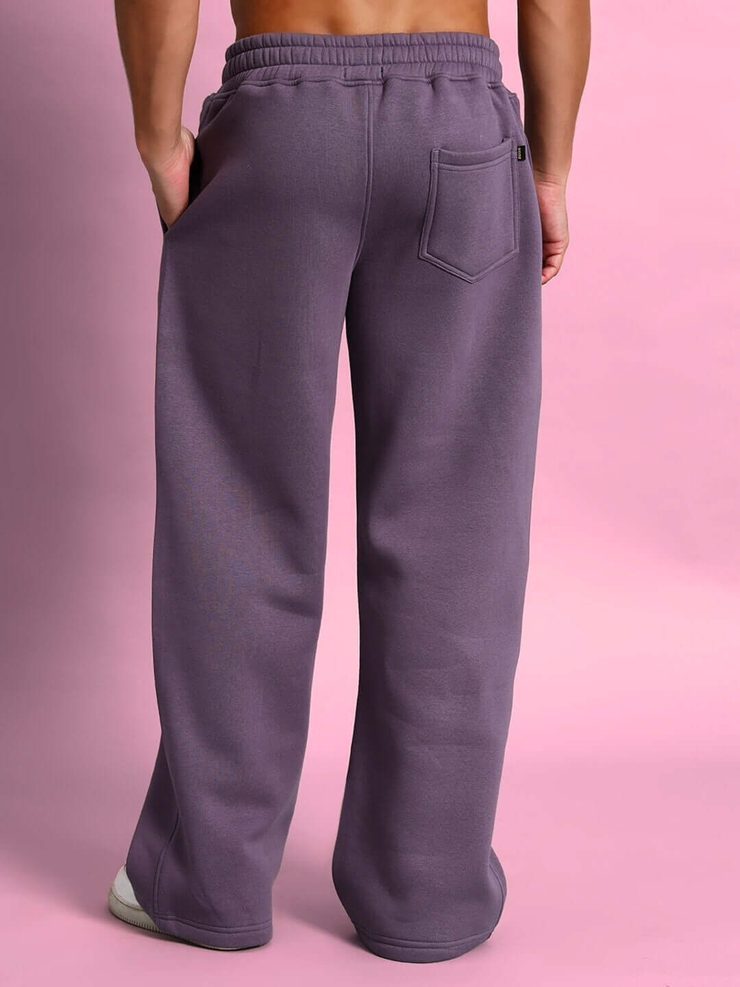 Rear view of CASPER Cotton Fleece Jogger in Violet, showcasing relaxed fit and back pocket detail against a pink backdrop.