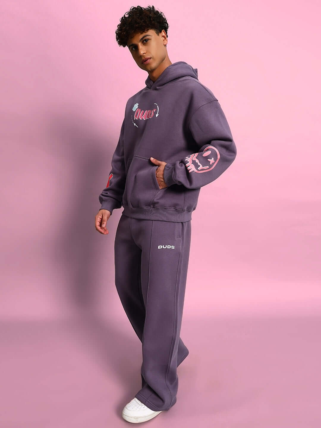 Person wearing Casper Cotton Fleece Jogger in Violet with a matching hoodie, standing against a pink background.
