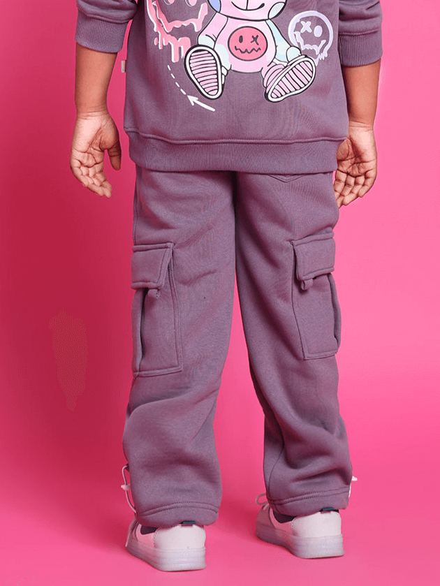 Child wearing violet Casper fleece pants with cargo pockets, standing on pink background.