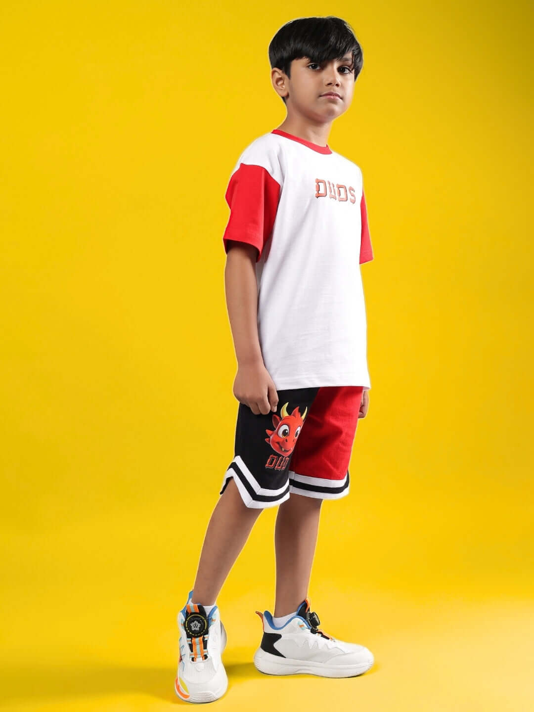 Boy wearing CASSIE CO-ORD FOR BOYS & GIRLS WHITE RED set, standing on yellow background. Casual and trendy kids fashion outfit.