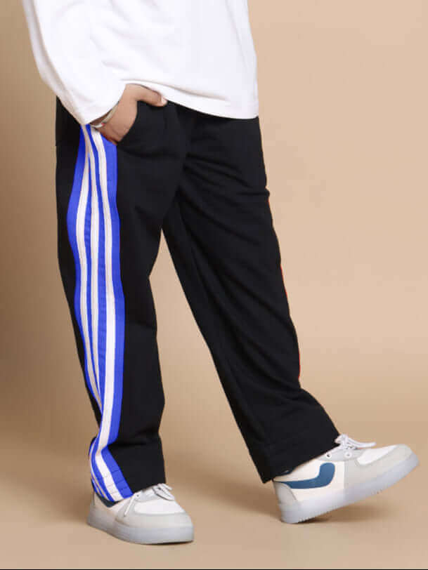 Child wearing white sneakers, black pants with blue stripes, and a white oversized sweatshirt.