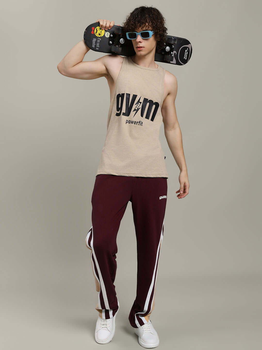 Person wearing RIO ONE relaxed fit joggers in brown, holding a skateboard and posing confidently in stylish casual attire.