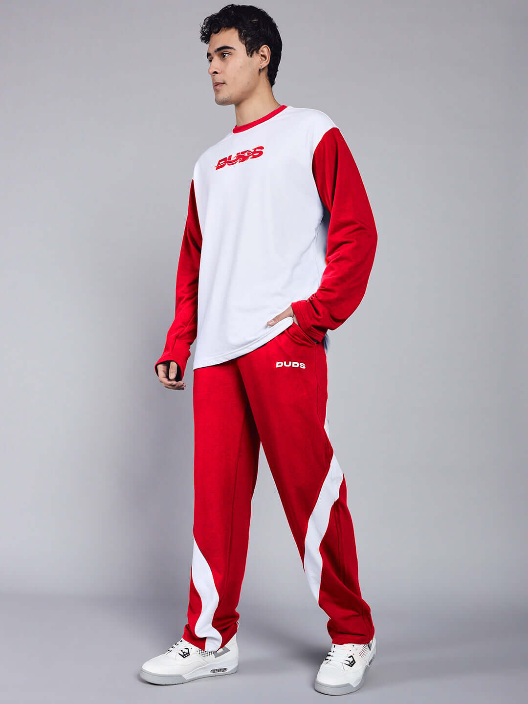Man modeling CELESTINE COOL RELAXED FIT CO-ORD SET WHITE RED with bold red and white design, showcasing streetwear fashion.