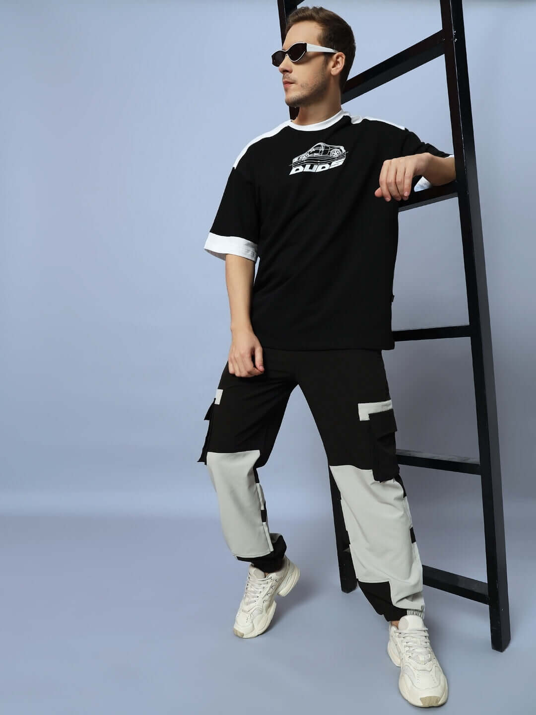 Model wearing Chalet Relaxed Fit Cargo Pants Black Grey with ladder background, showcasing casual style and multiple cargo pockets.