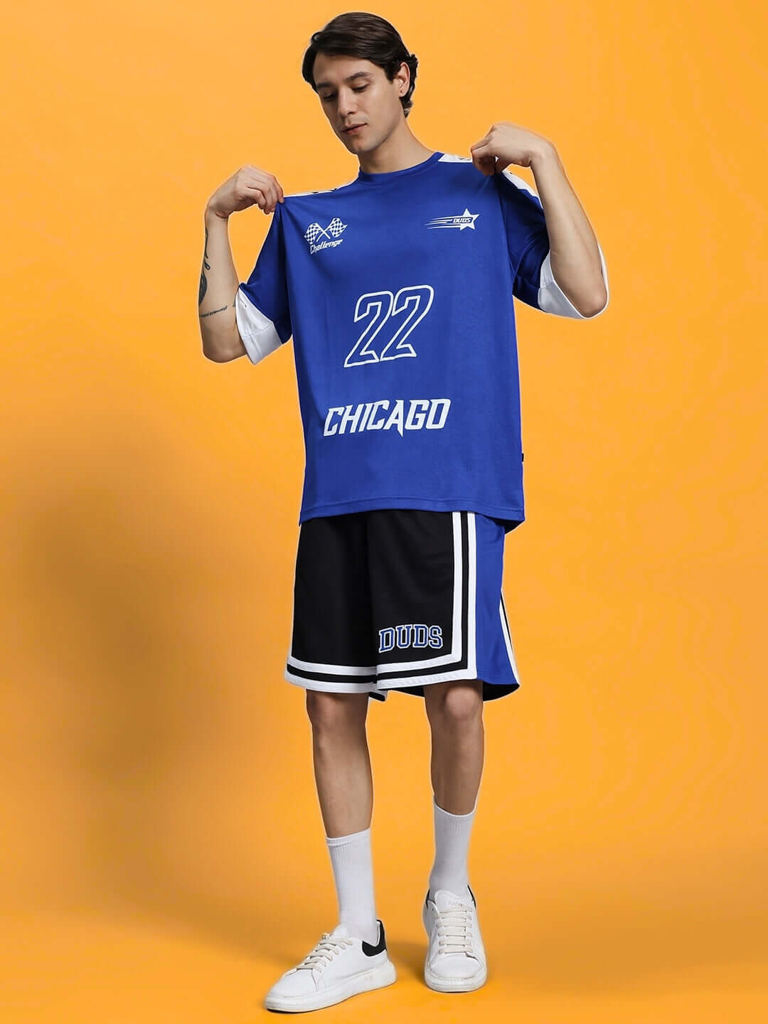 Man wearing a blue sports jersey with #22 and shorts, posing on an orange background.
