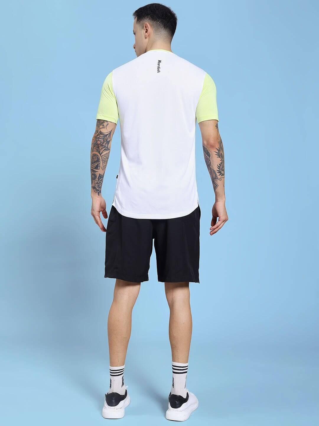 Back view of model wearing CHAMPION ZONE REGULAR FIT CO-ORD SET WHITE NEON BLACK, showcasing sporty design on blue background.