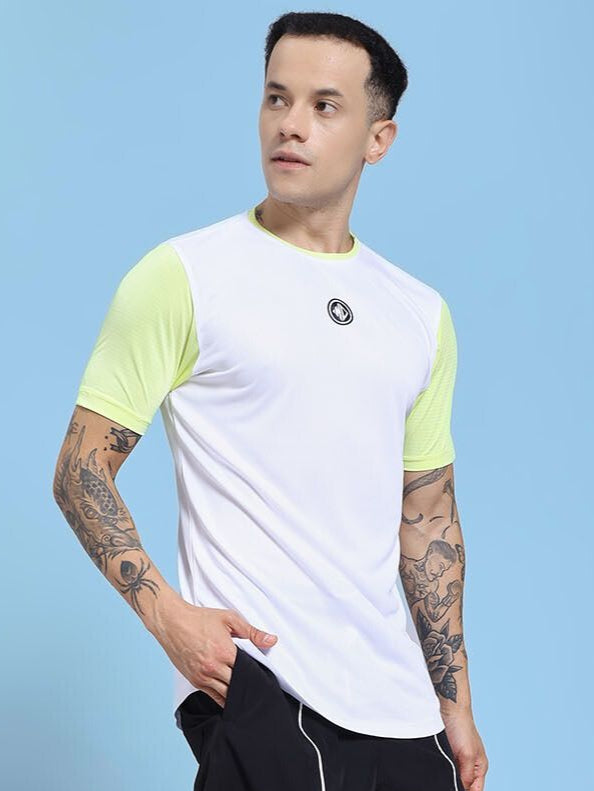 Man wearing CHAMPION ZONE REGULAR FIT T-SHIRT WHITE NEON GREEN with tattoos, standing on a blue background.