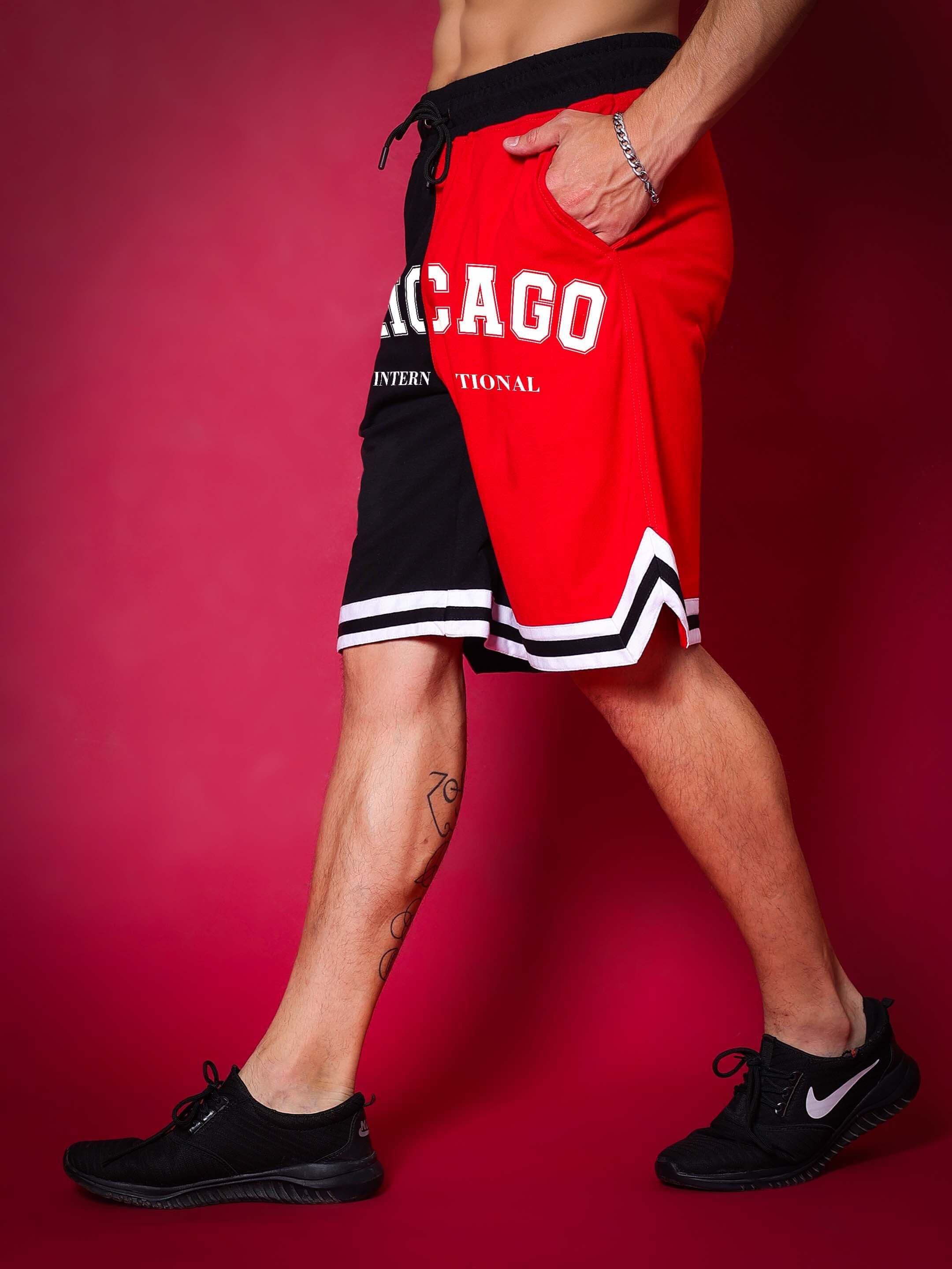 Model wearing Chicago Regular Fit Shorts in red and black with side view walking pose.