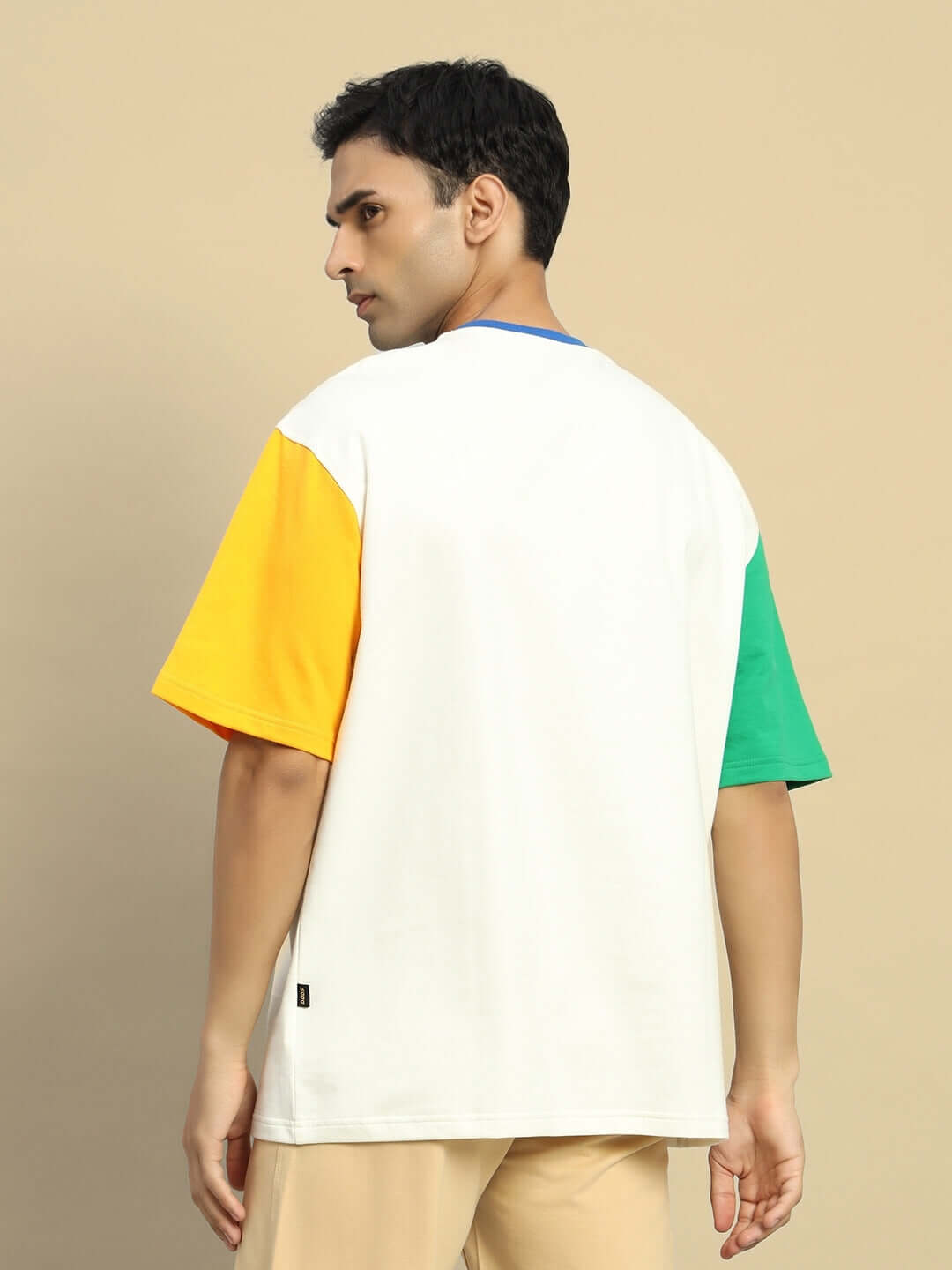 Man wearing Chroma Color Blocked Oversized T-Shirt in off white with vibrant sleeves, made from premium cotton French terry fabric.