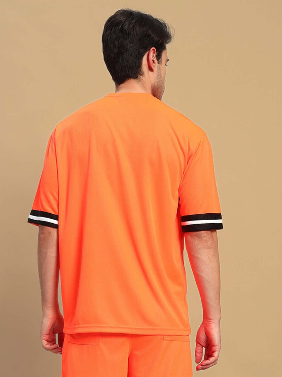 Back view of model wearing CHRONIC OVER-SIZED T-SHIRT ORANGE with black and white sleeve detail, casual streetwear fashion.