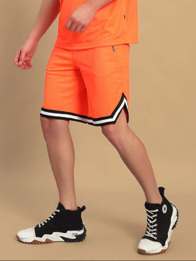 Person wearing CHRONIC REGULAR FIT SHORTS ORANGE with black and white sneakers, showcasing vibrant unisex style and comfort.