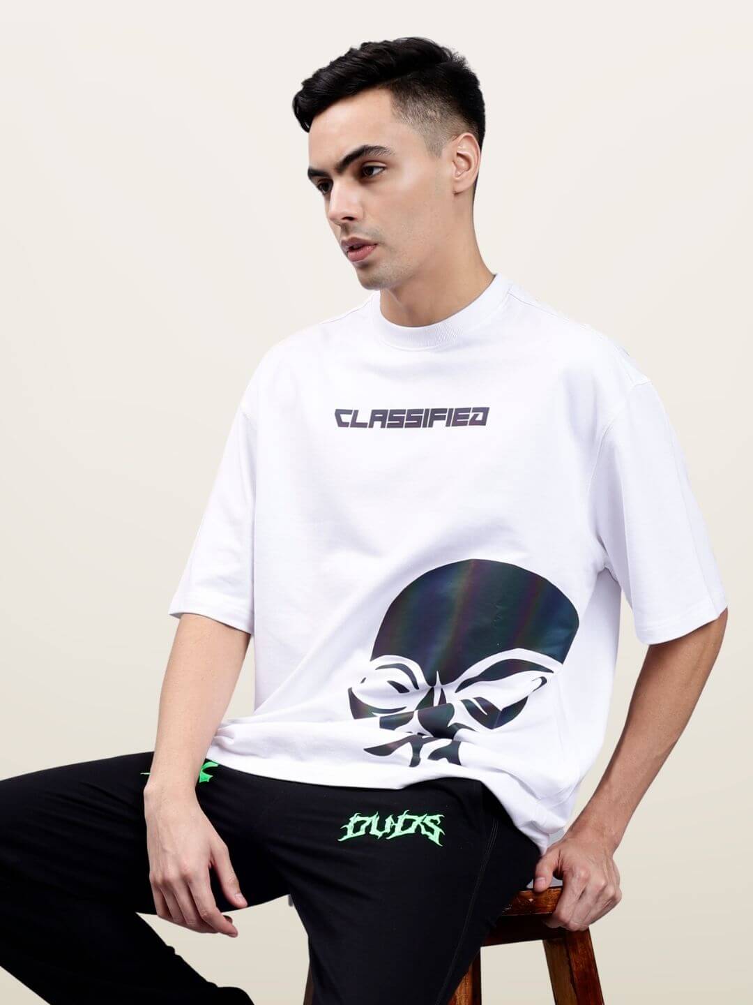 Model wearing oversized white t-shirt with 'CLASSIFIED' text, made of premium cotton blend, featuring a modern reflective design.
