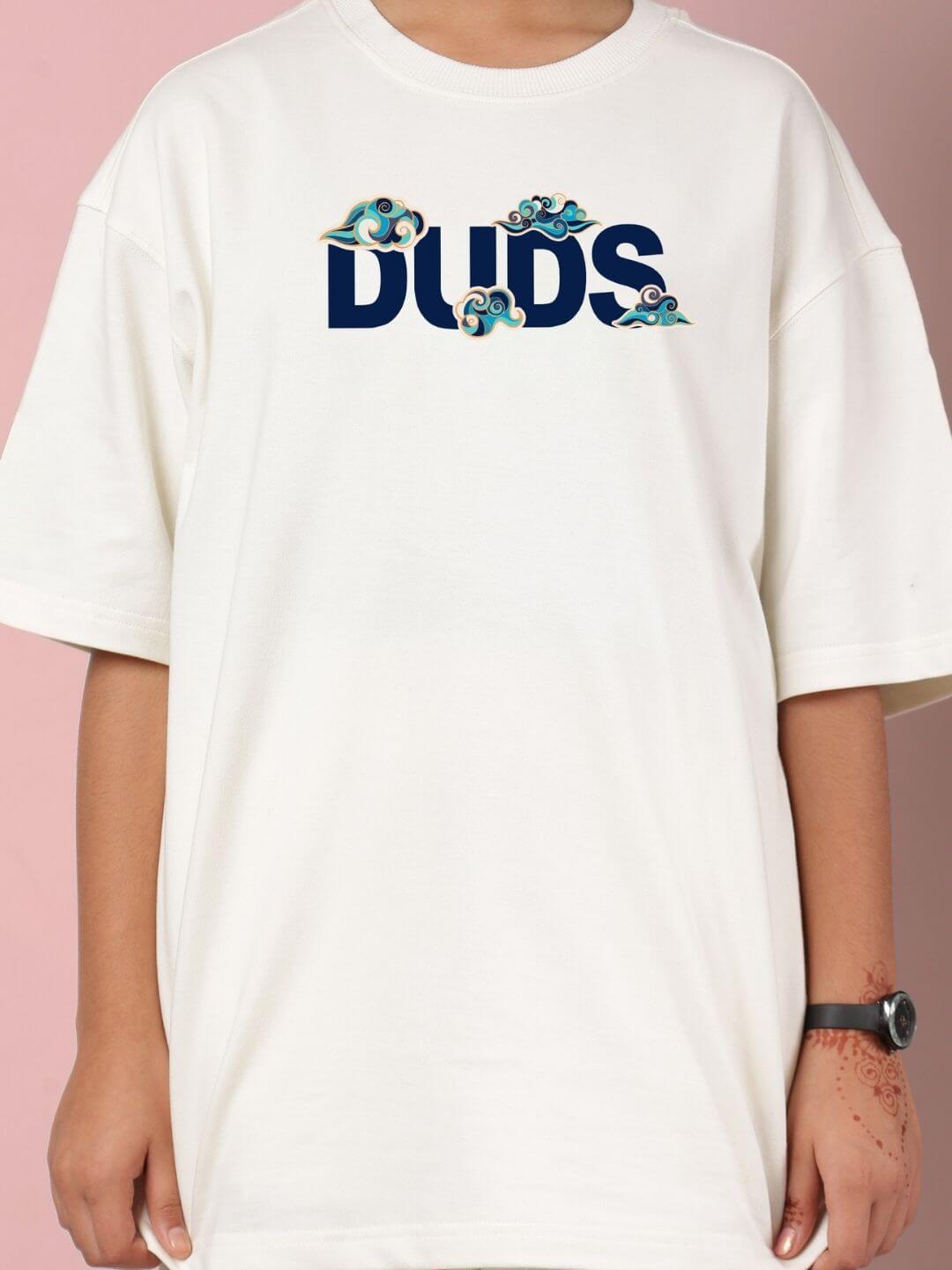 Child wearing an off-white t-shirt with the word 'DUDS' and cloud designs, part of the CLOUD PRINTED CO-ORD FOR BOYS AND GIRLS OFF WHITE set.