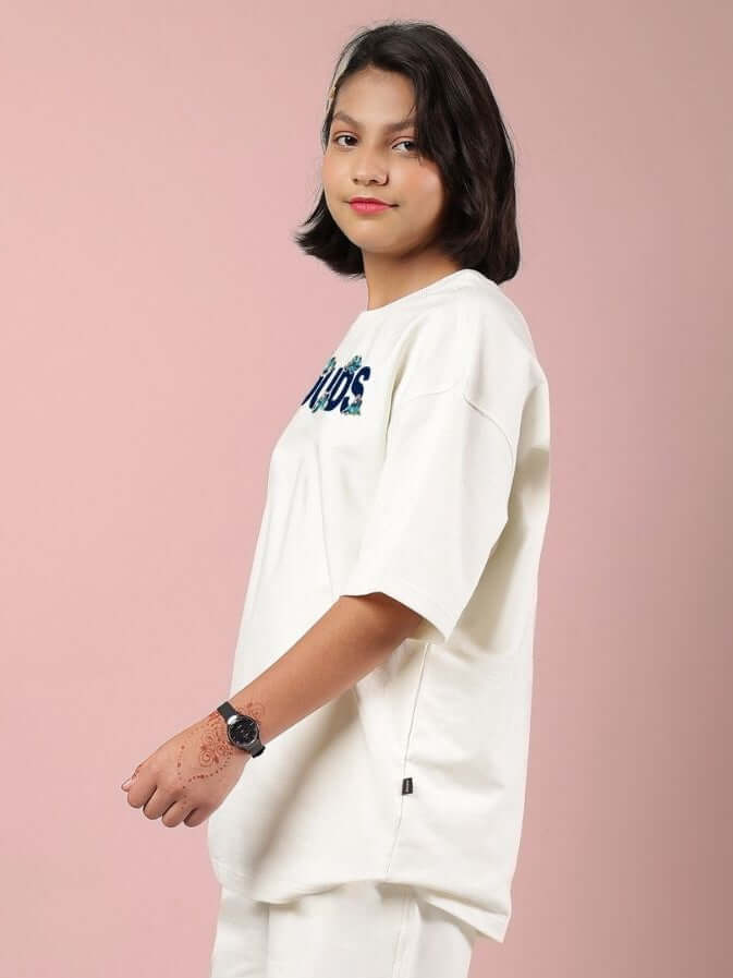 Child wearing CLOUD PRINTED OVERSIZED T-SHIRT FOR BOYS AND GIRLS OFF WHITE with cloud design on pink background.