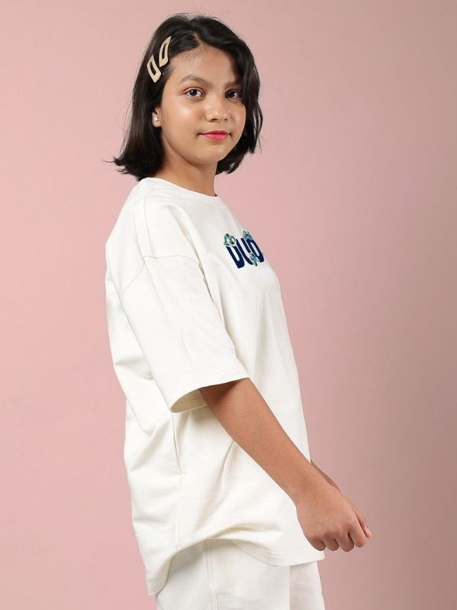 Child wearing CLOUD PRINTED OVERSIZED T-SHIRT FOR BOYS AND GIRLS OFF WHITE, featuring dreamy cloud pattern against pink background.