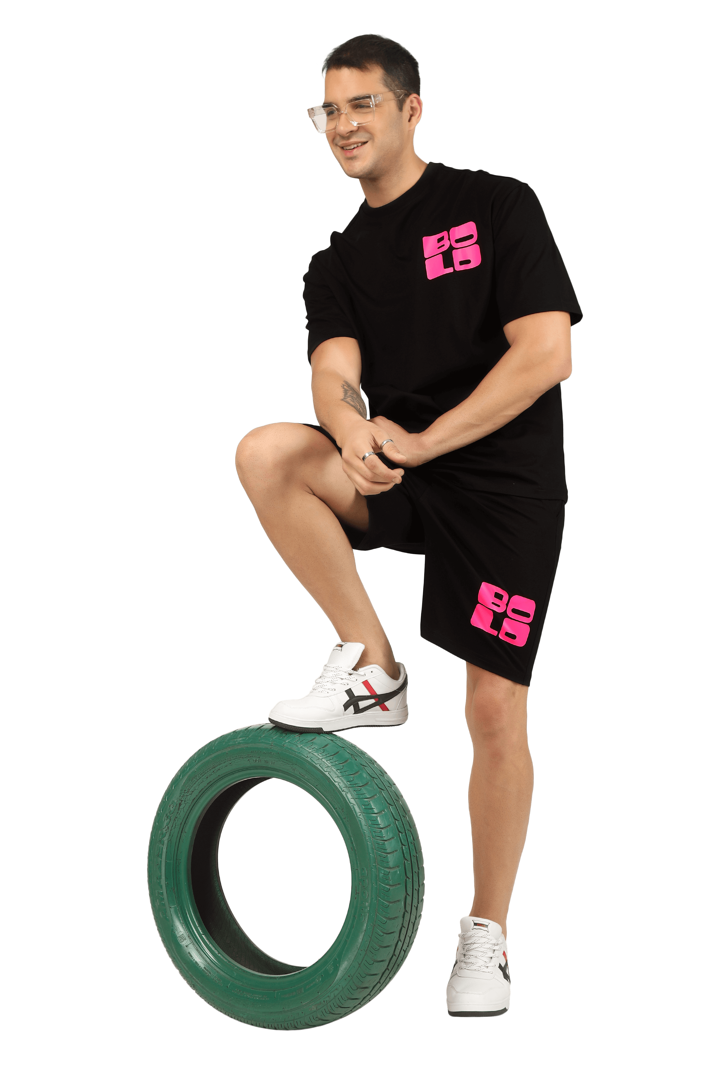 Model wearing a bold print CO-ORD set with pink accents, posing with one foot on a tire.