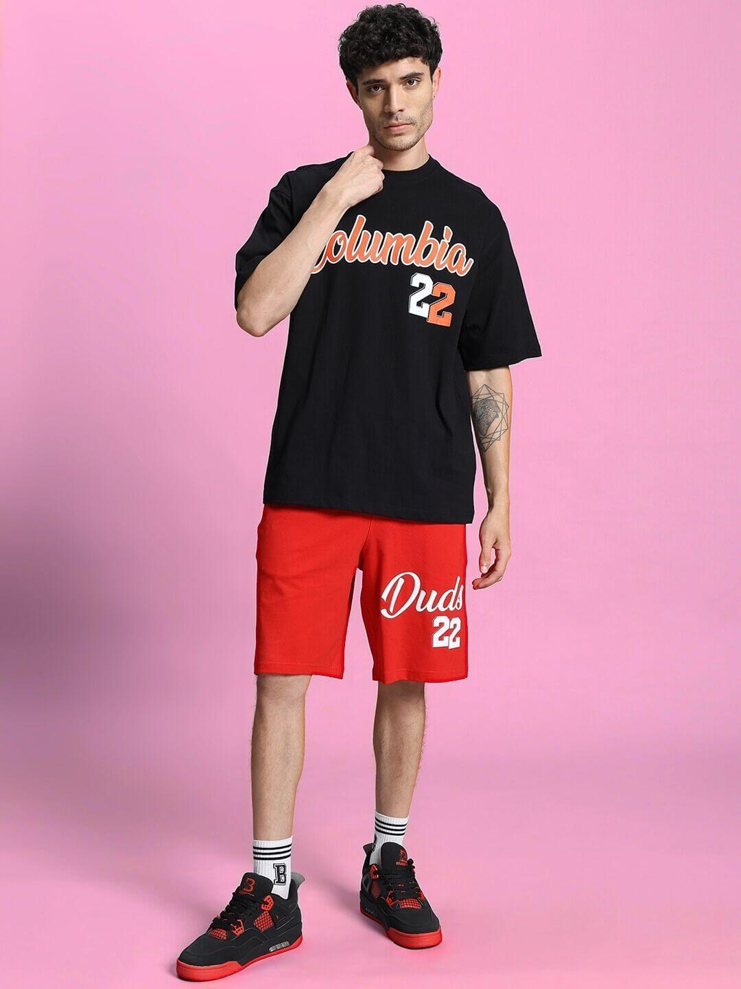 Model wearing COLUMBIA 22 PRINT SUMMER CO-ORD SET BLACK RED, featuring an oversized black tee and red shorts in a stylish streetwear look.