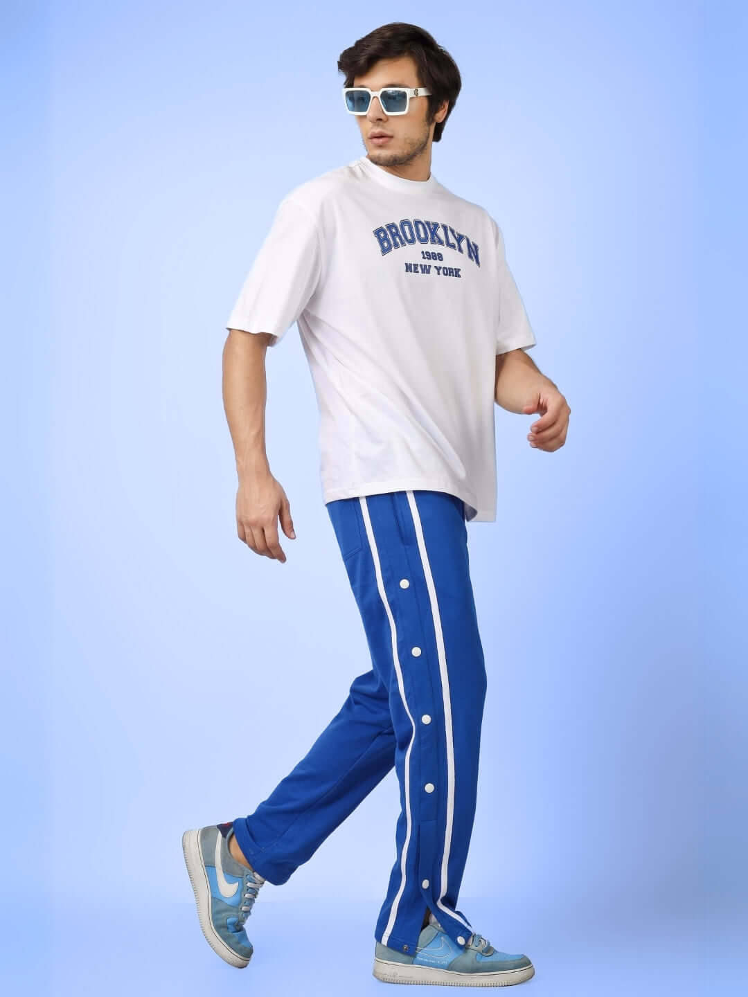 Man wearing contrast panel joggers in blue with a casual T-shirt and sunglasses