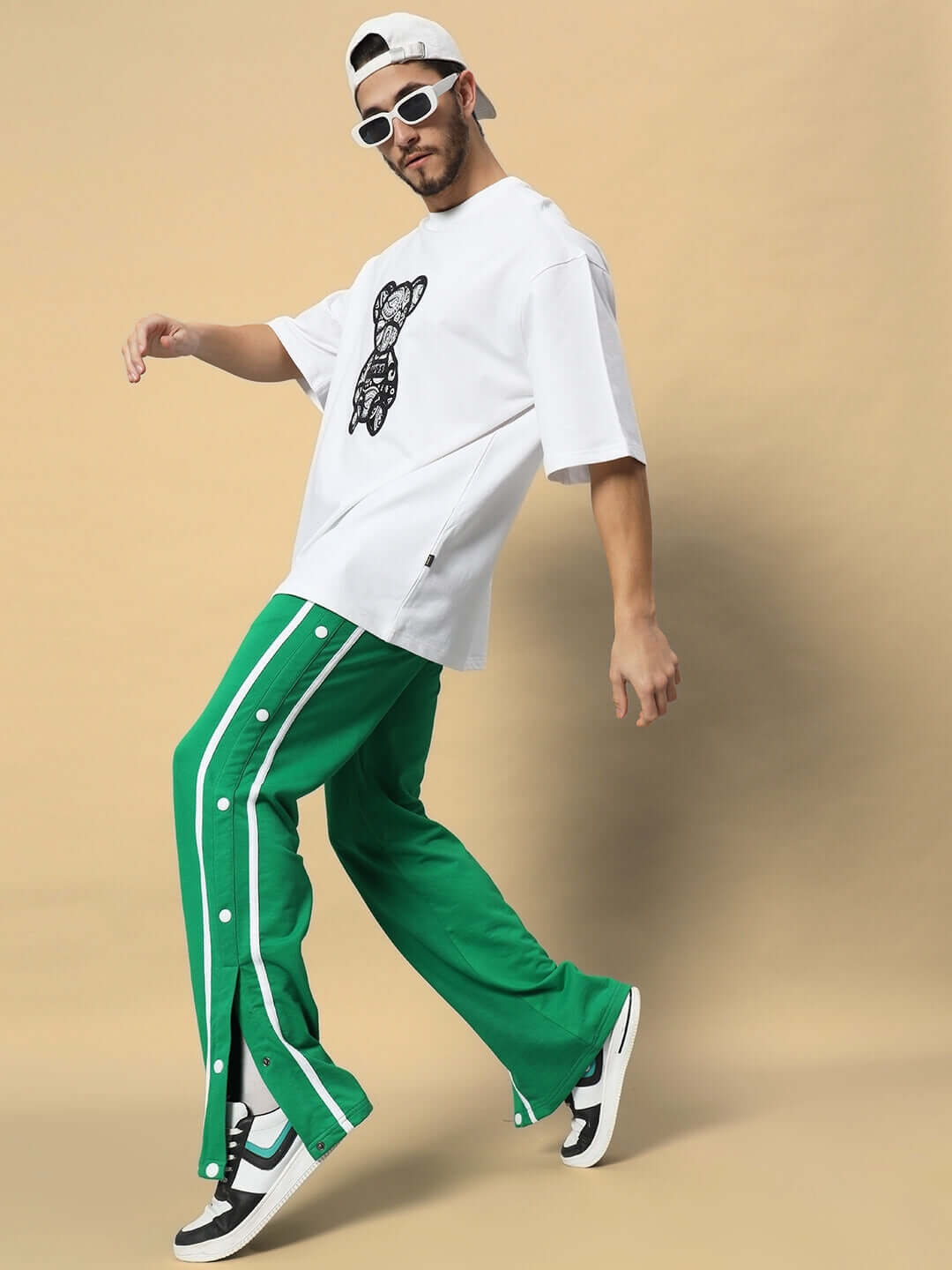Model wearing green contrast panel joggers paired with a white graphic tee and sneakers, perfect for casual fashion.