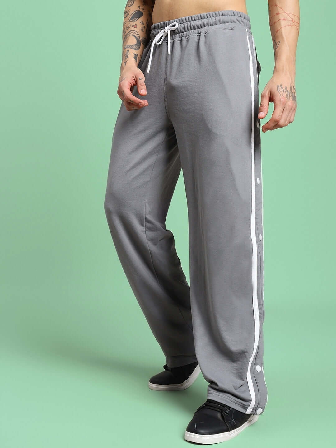 Model wearing CONTRAST PANEL COTTON TERRY JOGGER GREY with side stripe, showcasing comfortable fit and stylish design against green background.