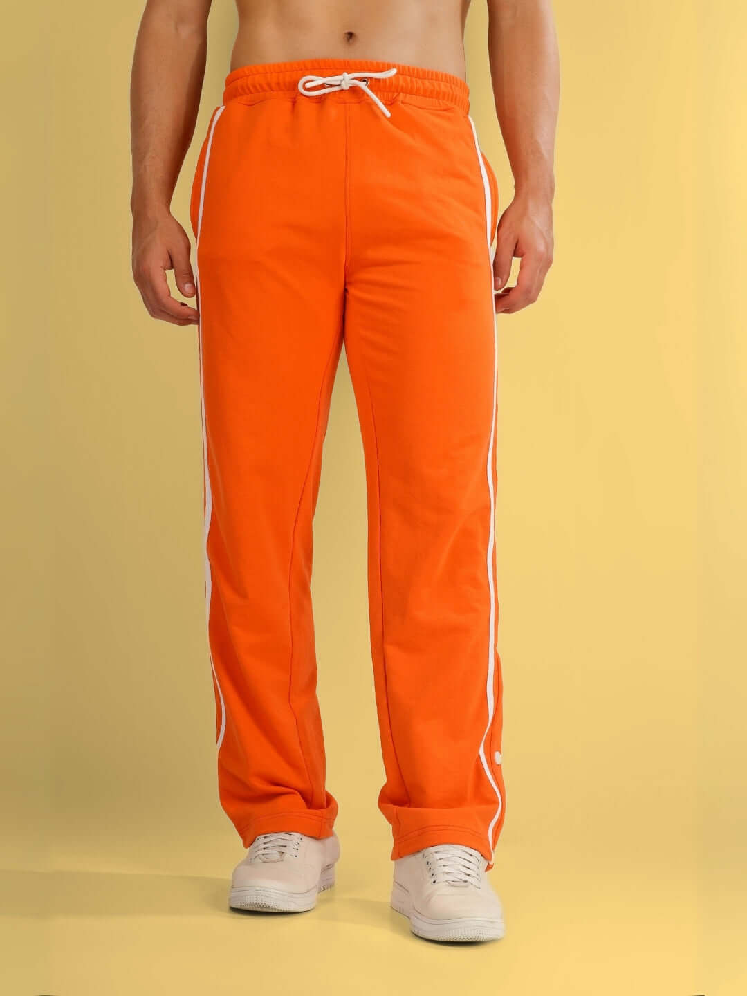 Person wearing orange contrast panel joggers from DUDS, made to order with custom fit options, featuring white side stripes.