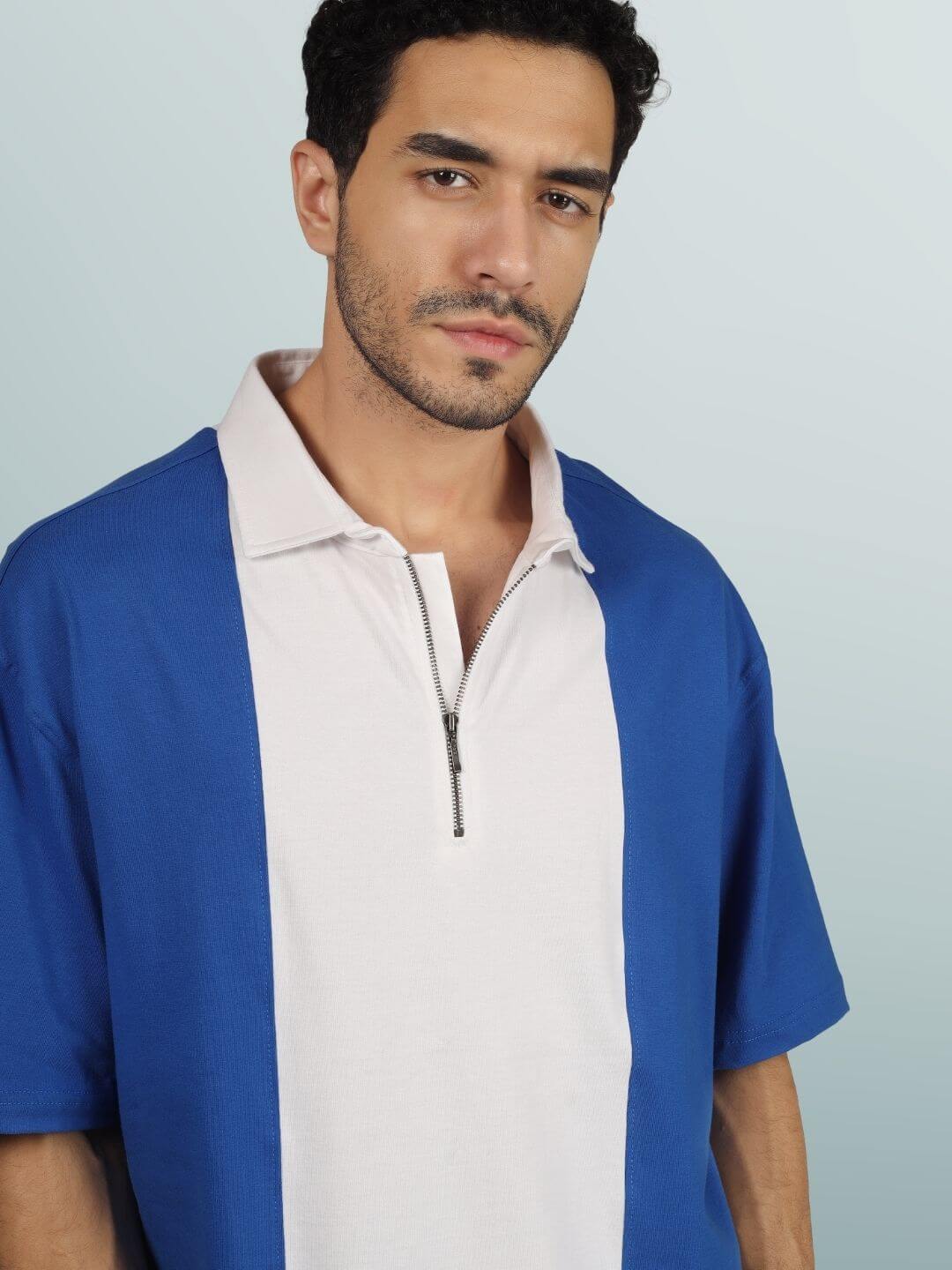 Model wearing blue-white contrast polo oversized zipper T-shirt, half sleeves, premium cotton fabric, stylish and comfortable fit.