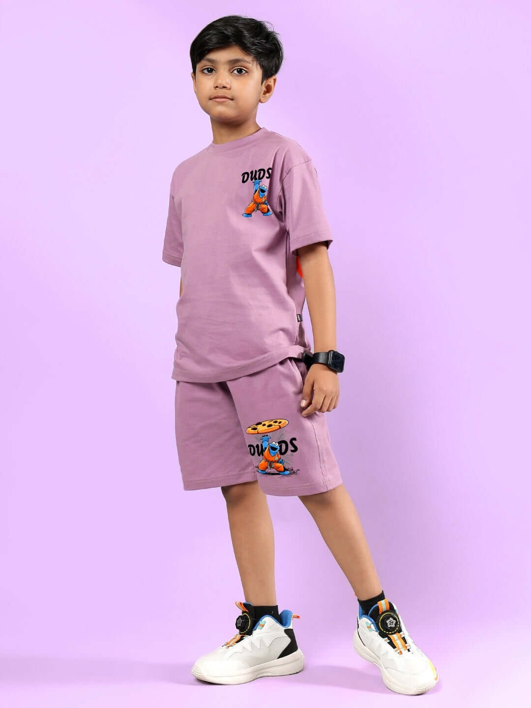 Child wearing COOKIE MONSTER PRINTED CO-ORD FOR BOYS & GIRLS PLUM PURPLE with DUDS logo on lilac background.