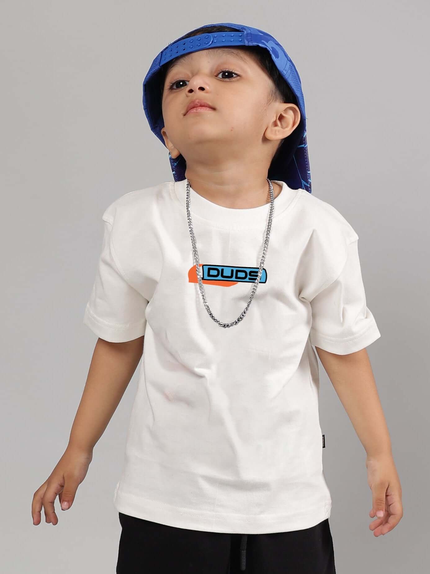 Child wearing a white ROBO SHARK t-shirt for boys and girls, paired with a blue cap and chain necklace.