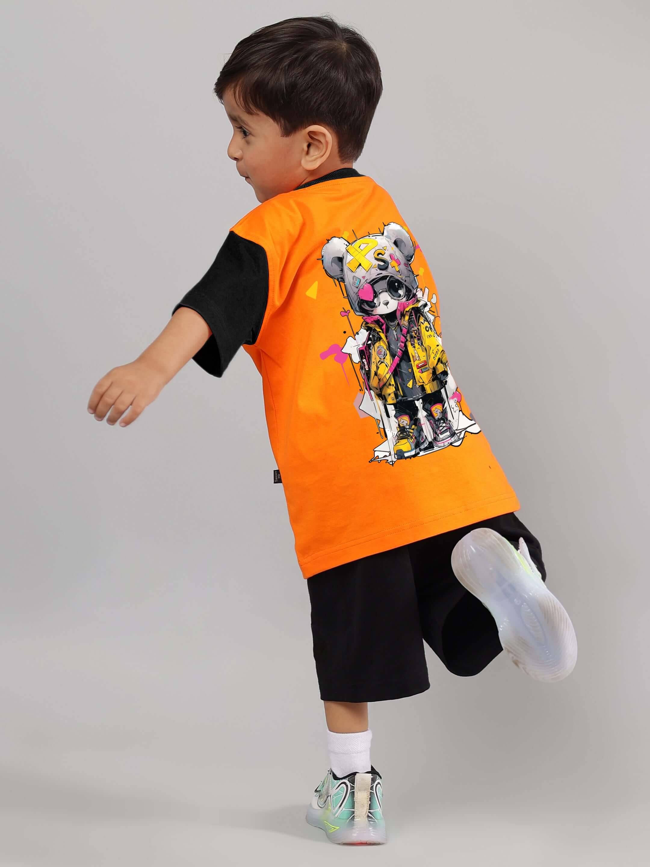 Child wearing orange COOL TEDDY T-shirt with playful teddy bear design, perfect for boys and girls, made to order by DUDS tailors.