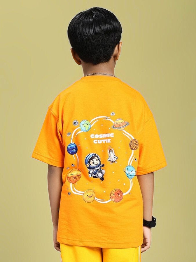Child wearing COSMIC CUTE ASTRONAUT T-SHIRT FOR BOYS AND GIRLS ORANGE with astronaut and planet graphic.