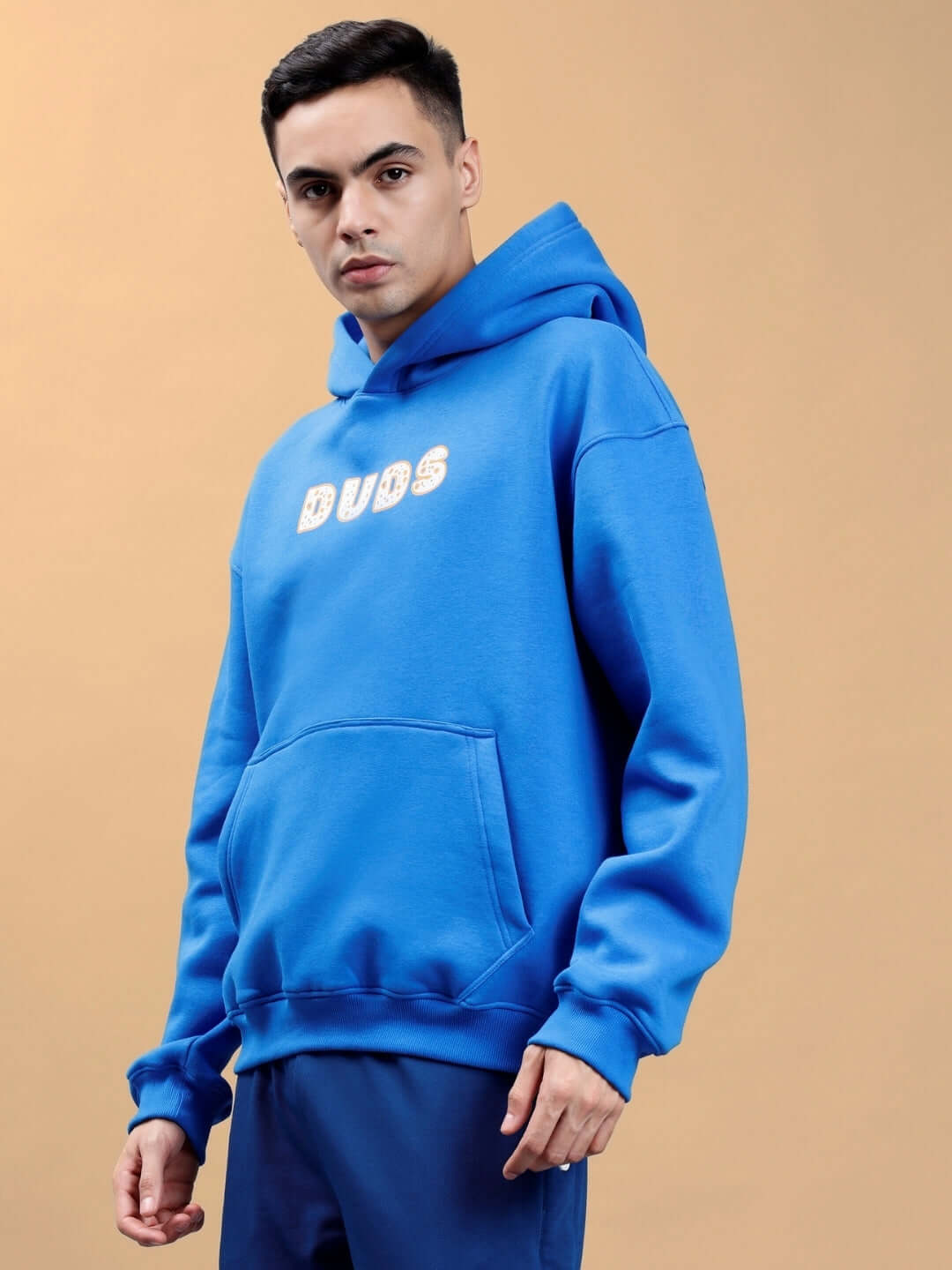 Man wearing a royal blue oversized hoodie with 'BUDS' text, stylish casual outerwear for cool weather.