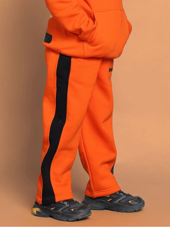 Orange Courage fleece pants for boys and girls with black stripe, comfortable fit, shown in casual setting.