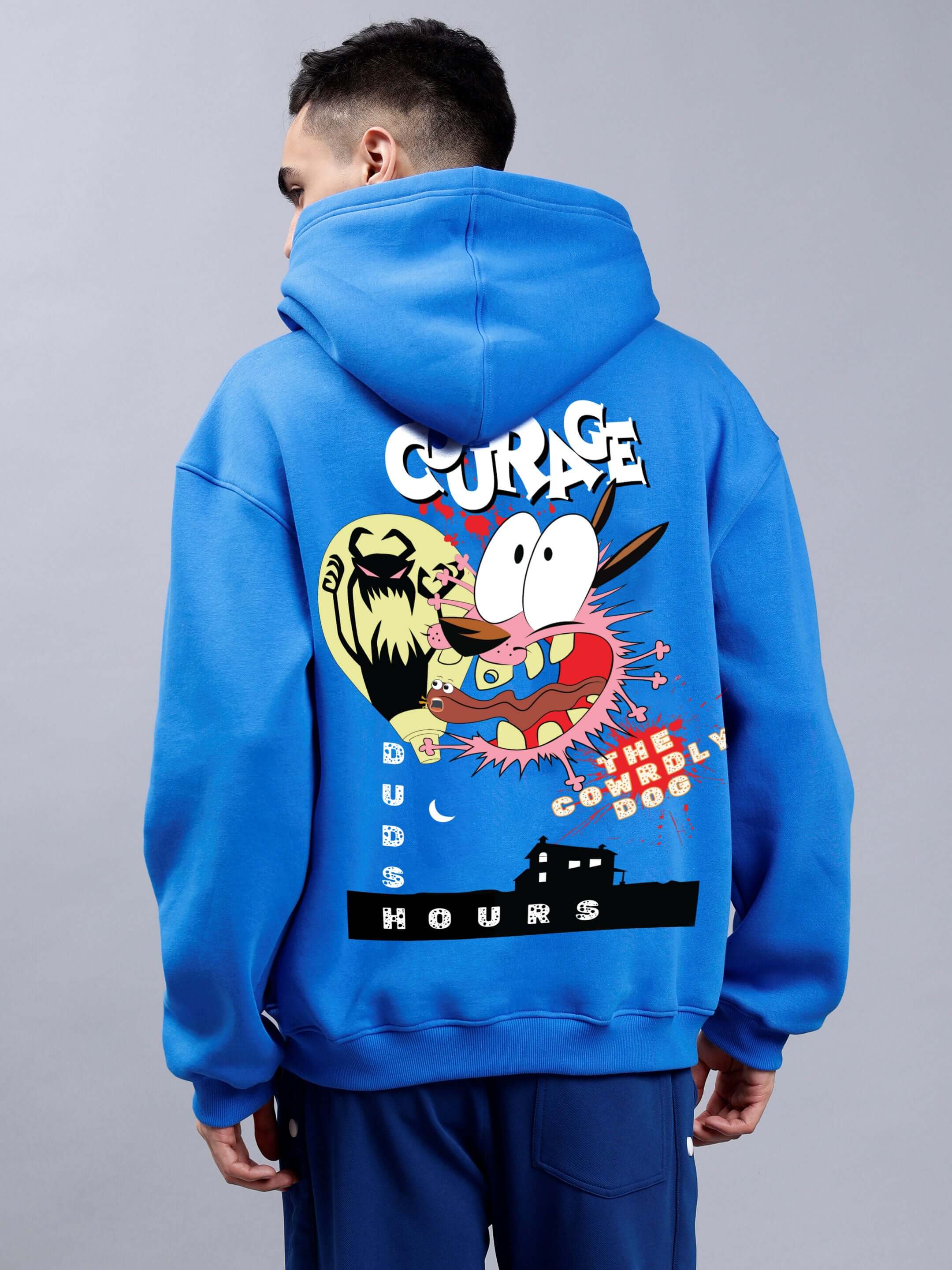 Man wearing royal blue oversized hoodie with 'COURAGE' graphic design on the back, featuring colorful cartoon characters and text.