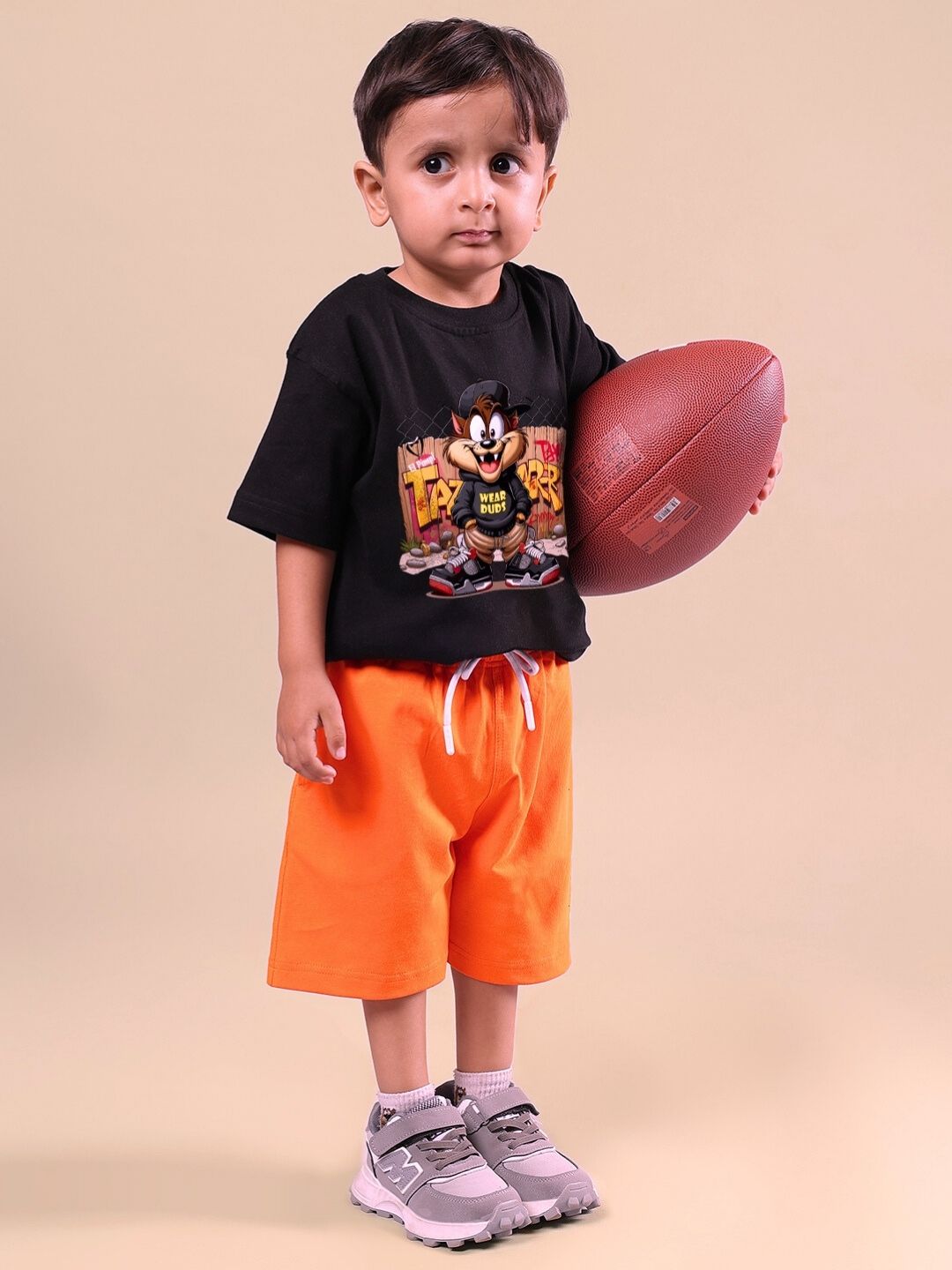 Young child wearing Crazy Rapper black and orange co-ord set, holding a football. Perfect for kids' hip-hop street style fashion.